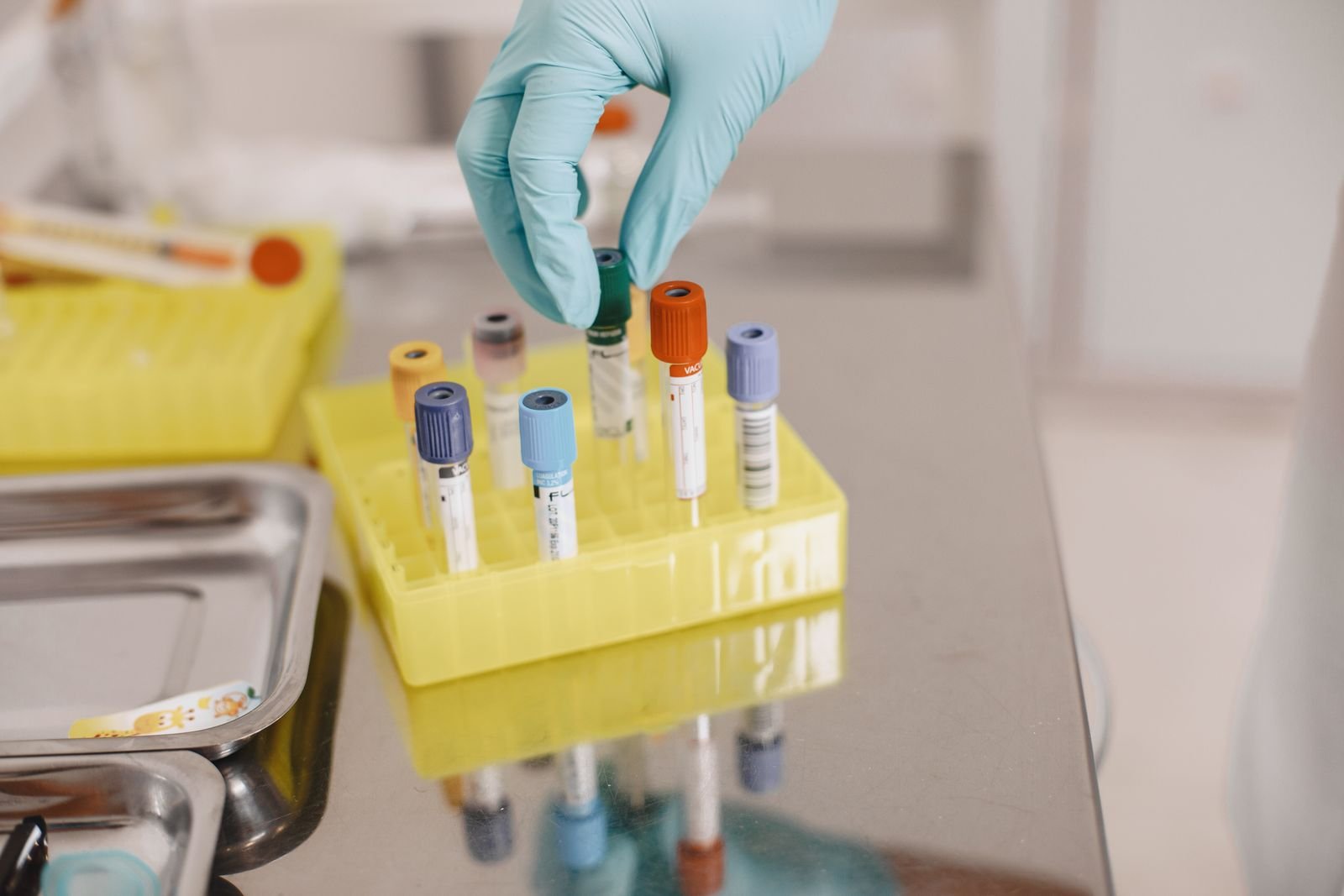 A gloved hand placing sample tubes in a rack in a laboratory