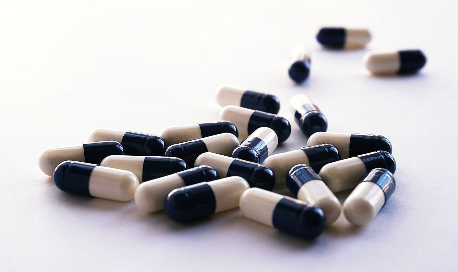 Two-coloured medicine capsules scattered on a white surface